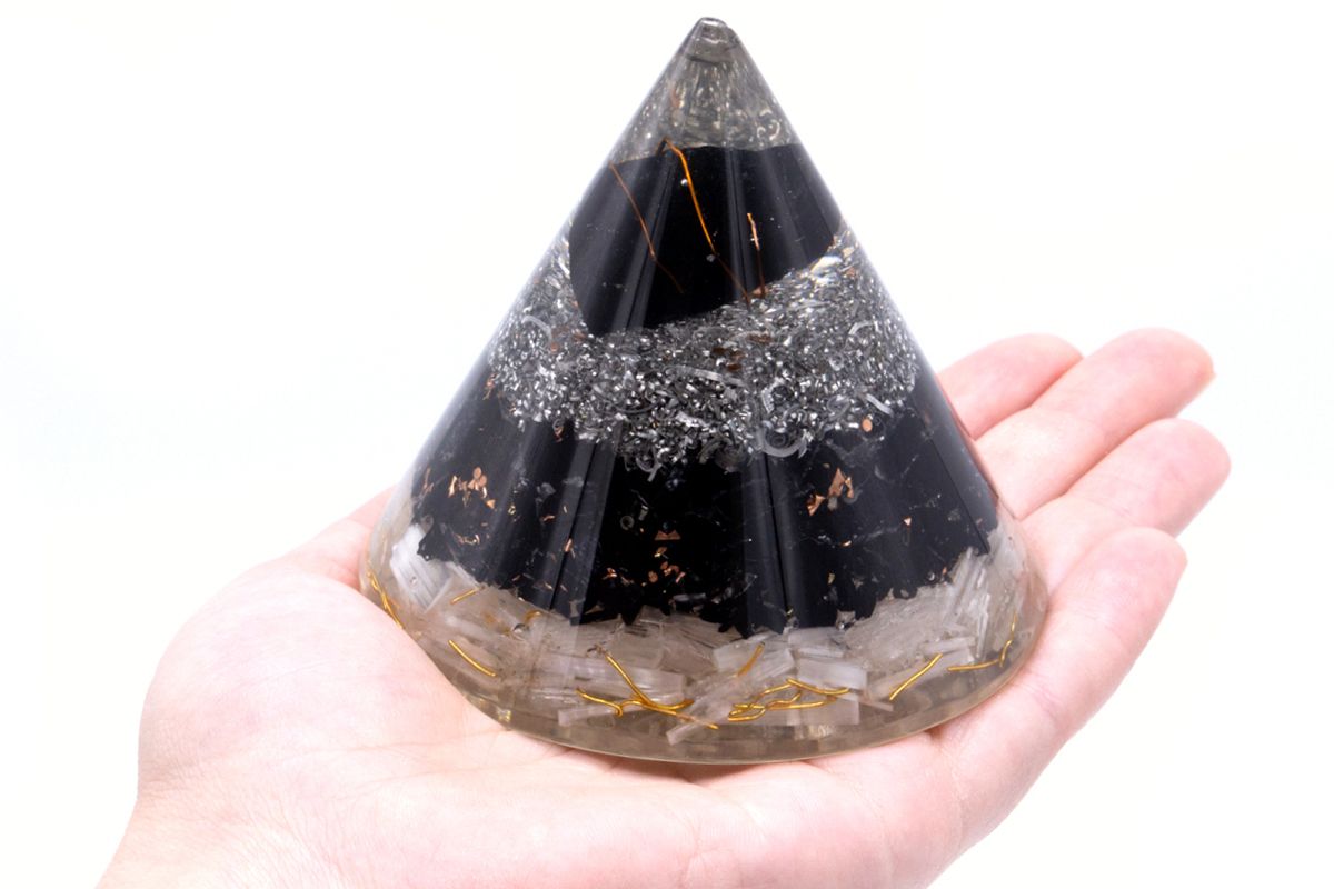 Black tourmaline, selenite and copper Orgonite cone in palm of hand