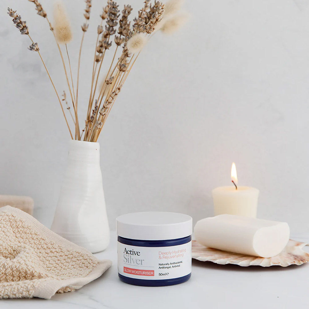 Active Silver Glow Moisturiser 50ml on table with candle