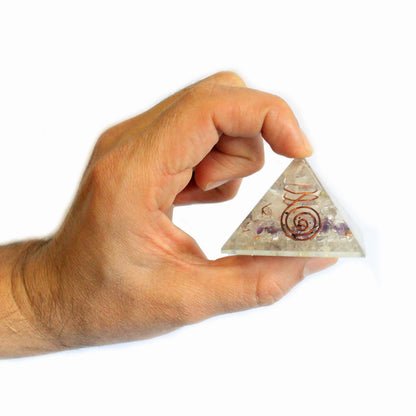 Hand holding orgonite pyramid with gemstones