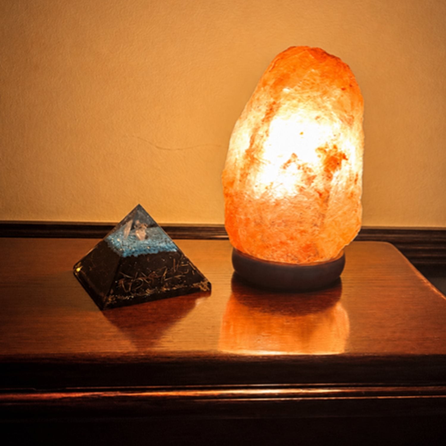 Himalayan salt lamp next to orgonite pyramid on shelf