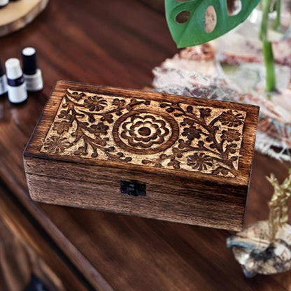 Hand carved mango wood essential oil storage box on a table with oils