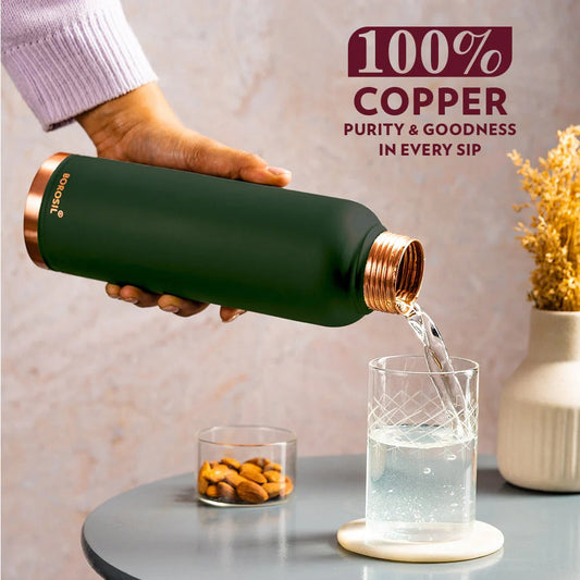Water being poured from a Borosil copper bottle with green exterior and 100% copper text