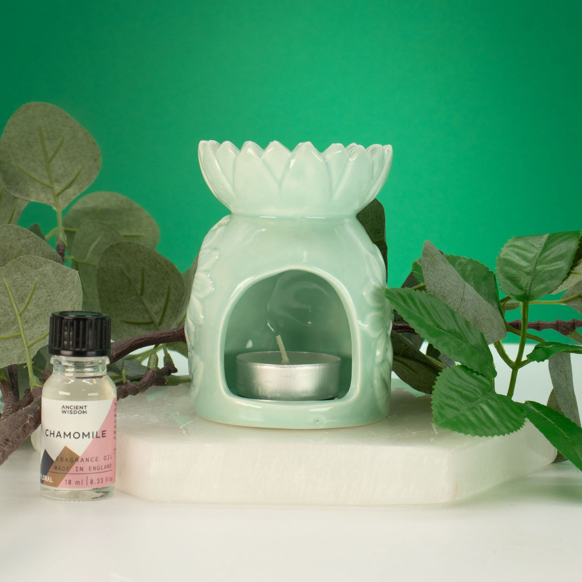 Ceramic sunflower oil burner in pastel green on table with tea light