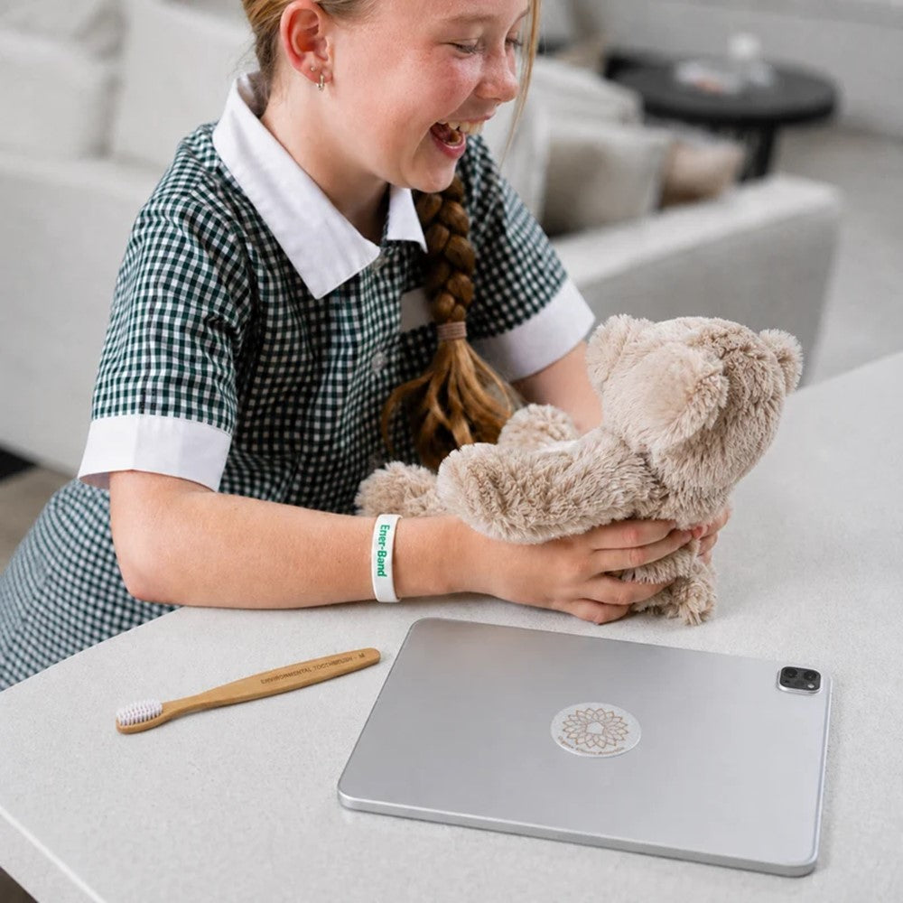 Child cuddling her Ener bear harmoniser near a laptop computer